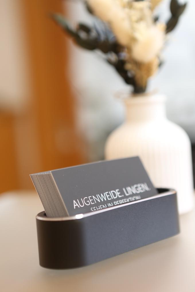 Visitenkarten der Augenweide Lingen neben einer Vase auf dem Empfangstresen